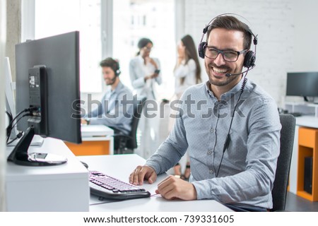 Happy young male customer support executive working in office. Royalty-Free Stock Photo #739331605