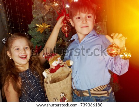 Happy little kids  decorate Christmas tree in beautiful living room with traditional fire place. 