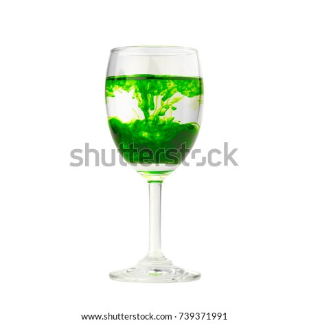 Green food coloring diffuse in water inside wine glass isolated on white background.