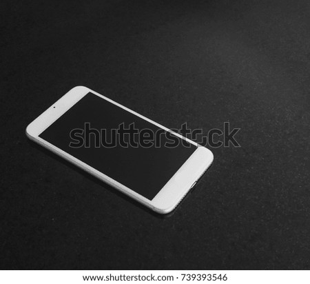 White smartphone on black marble table, black screen
