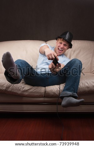 young man leaning while playing video games on gray background