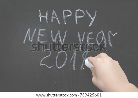 Happy New Year 2018 hand written with white chalk on the blackboard. Children hand finish to write year 2018. concept of new year holiday at school  