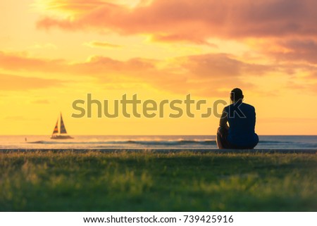 Peaceful moments. Thoughtful man sitting watching the sunset and sale boat go by. Royalty-Free Stock Photo #739425916
