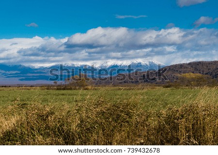 Boundless field of yellow fall grass. A little mountains are on background. Wonderful day with blue sky.