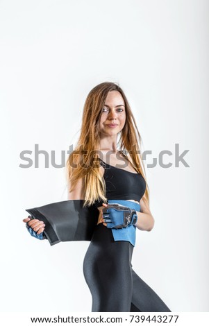 Pretty dark hair girl, wearing a black top and leggins, wears blue belt around her back in the white isolated studio background