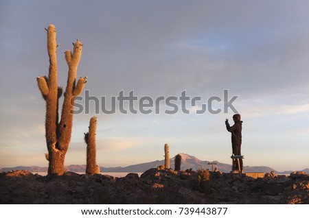 Tourist taking a picture of a cactus with his camera on Incahuasi island at sunrise