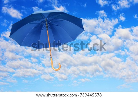 Wind of change concept.Blue umbrella flies in sky against of white clouds.Mary Poppins Umbrella. Royalty-Free Stock Photo #739445578