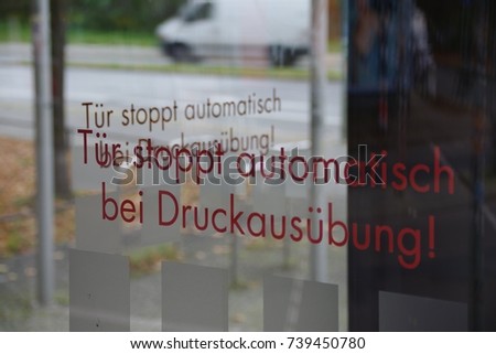 Revolving Glass Door Inscription: (Translation: "Door stops automatically if pressure is applied")