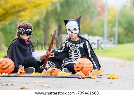 Two children, boy brothers in the park with Halloween costumes, having fun