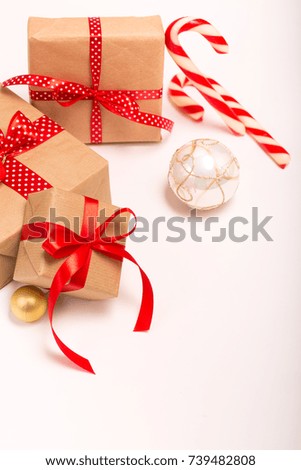 Christmas gift boxes wrapped in craft paper with satin red ribbon bow for christmas present celebration box on white isolated background copy space greeting card frame candy canes white ornament balls