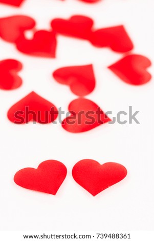 Two red hearts isolated on white background with red hearts in the background.