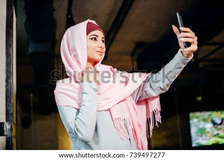 Arabian muslim woman taking selfie with phone in cafe