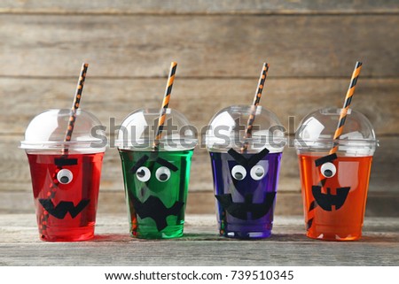 Halloween cocktail in plastic cups on grey wooden table