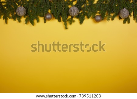 Yellow background with ornaments on fir tree branches. Chrismas and New Year.