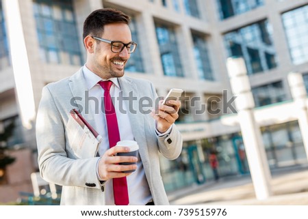 Attractive business man in suit and eyeglasses using his mobile phone.