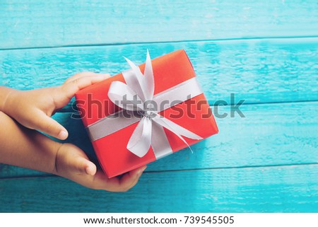 Hands holding red gift box with as a present for Christmas, new year, valentine day or anniversary on wood background selective focus.