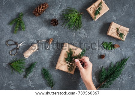 Christmas workspace. Girl's hands making christmas gifts on black background. Flat lay, top view