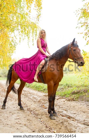 Girl with a horse walking in an autumn forest