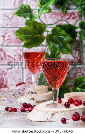 Transparent red drink with cranberries on a wooden background. Selective focus.