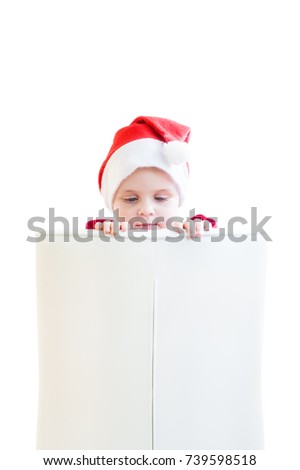 The kid in the Santa Claus hat holds his hands on the back of the white chair and looks at them. Because of the back, only the head of the child is visible. White background