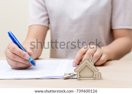 Woman hand and home key. Signed contract and keys of the property with documents. Concept for real estate business.