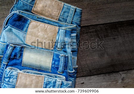 Blue jean and jean lack texture on the wooden floor, Pattern of blue jeans are overlapping on the table.