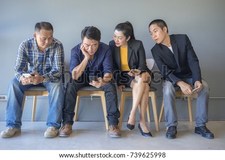 Two men and a woman are look sideways at a friend's phone. 
