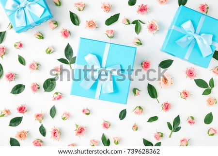 Closed blue gift boxes collection with pink roses on a white background in flat lay style. Top view