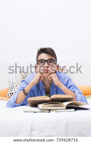 teenage boy with books in bed studying