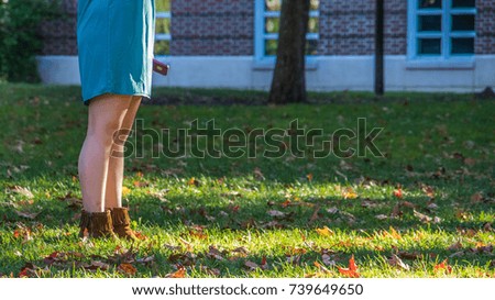 Woman in squirt  is standing among falling autumn leaves
