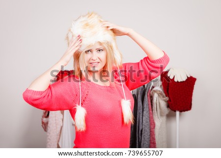 Outfit for cold days ideas, fashion and clothing concept. Attractive smiling blonde woman in wardrobe, picking clothes wearing furry winter hat