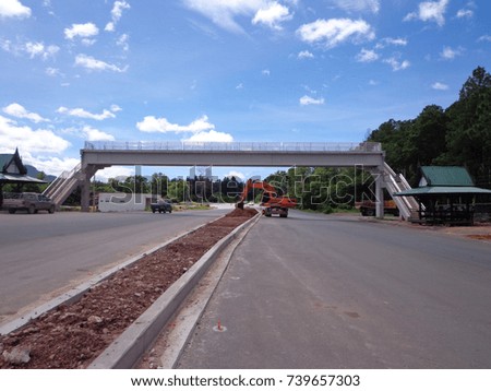 Bridge across the road, orange excavator working on the highway