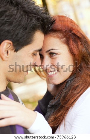 Love and affection between a young couple at the park in autumn season (selective focus with shallow DOF)