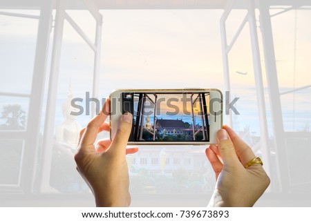 Take a picture of someone taking a cellphone through a window of your home. While photographing a temple with a large Buddha image telephone towers and Solar Cell,And the background blurred. 
