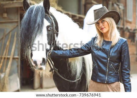 Beautiful country style blond woman with black and white horse.