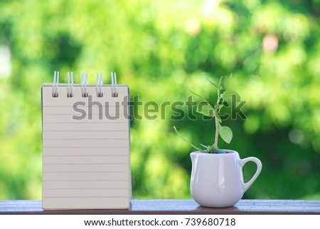 notepad and coffee cup on tree blurry background.using wallpaper or background for education, business photo. Take note of the product for food with drink image and concept or copy space.