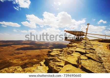 The bottom of Ramon Crater (Makhtesh Ramon), the largest in the world, as seen from the high rocky cliff edge surrounding it from the north, Ramon Nature reserve, Mitzpe Ramon, Negev desert, Israel Royalty-Free Stock Photo #739690660