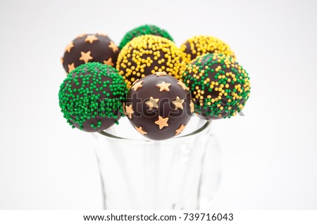 Chocolate cake pops in glass, decorated with colorfull confectionery sprinkles on a white background. Picture for a menu or a confectionery catalog.