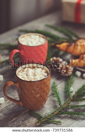 hot cocoa with marshmallows and croissant on rustic wooden table with christmas lights. Cozy winter home concept