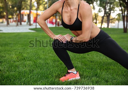Cropped picture of amazing strong young sports woman standing outdoors make sports exercises.