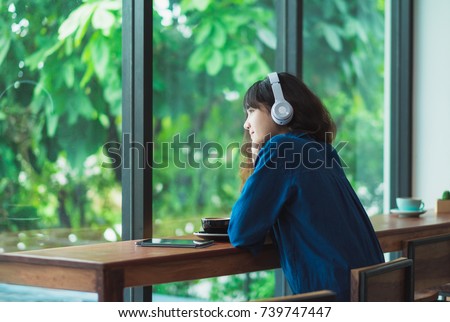 Happy asian casual woman listening music with headphones near window at cafe restaurant,Digital age lifestyle,chill out  life
