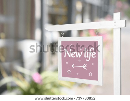 Signboard with text NEW LIFE in front of house