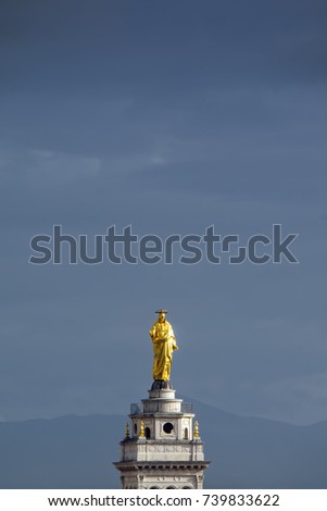 Golden statue of Jesus Christ above the Church of the Sacred Heart of Jesus at the Praetorian Barracks against the dramatic blue sky background, Rome, Italy
