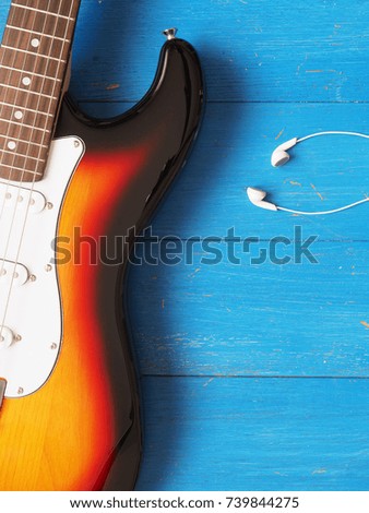 Music concept image, vintage guitar with earphones on a rustic wooden background, Jazz, rock or blues music concept