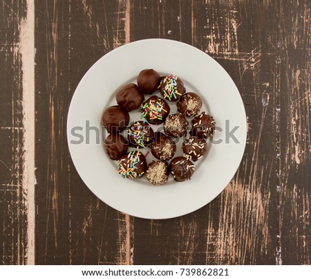 Four different Healthy Homemade chocolate truffles with dates, apricots, hazelnuts and raisins served on white plate on wooden background (photo from above)