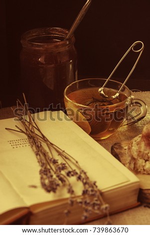 Breakfast: black tea with lemon and strawberry jam. A book with a bouquet of lavender. Vintage picture