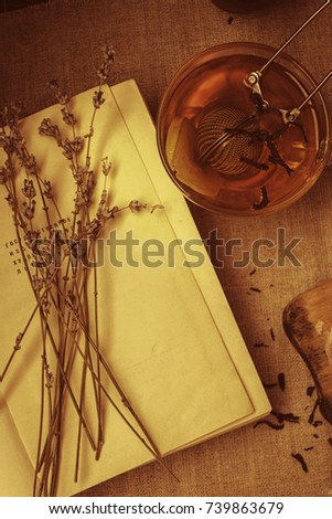 Black tea with lemon and a strainer, and a book with a bouquet of dry lavender. Vintage picture. Flat lay
