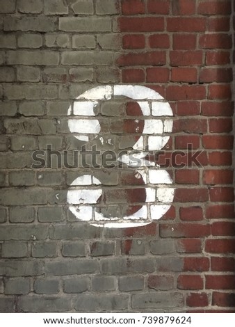 Number three painted on a brick wall