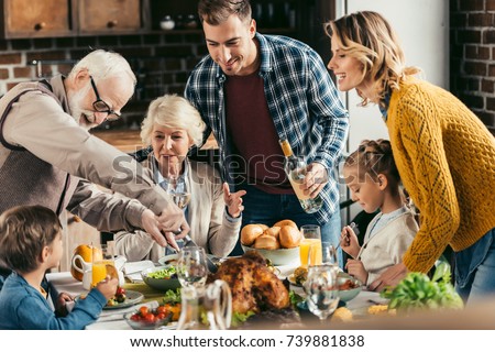 family having holiday dinner and cutting turkey