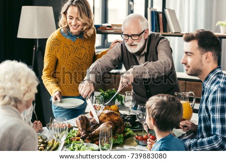 grandfather cutting turkey for family on thanksgiving dinner